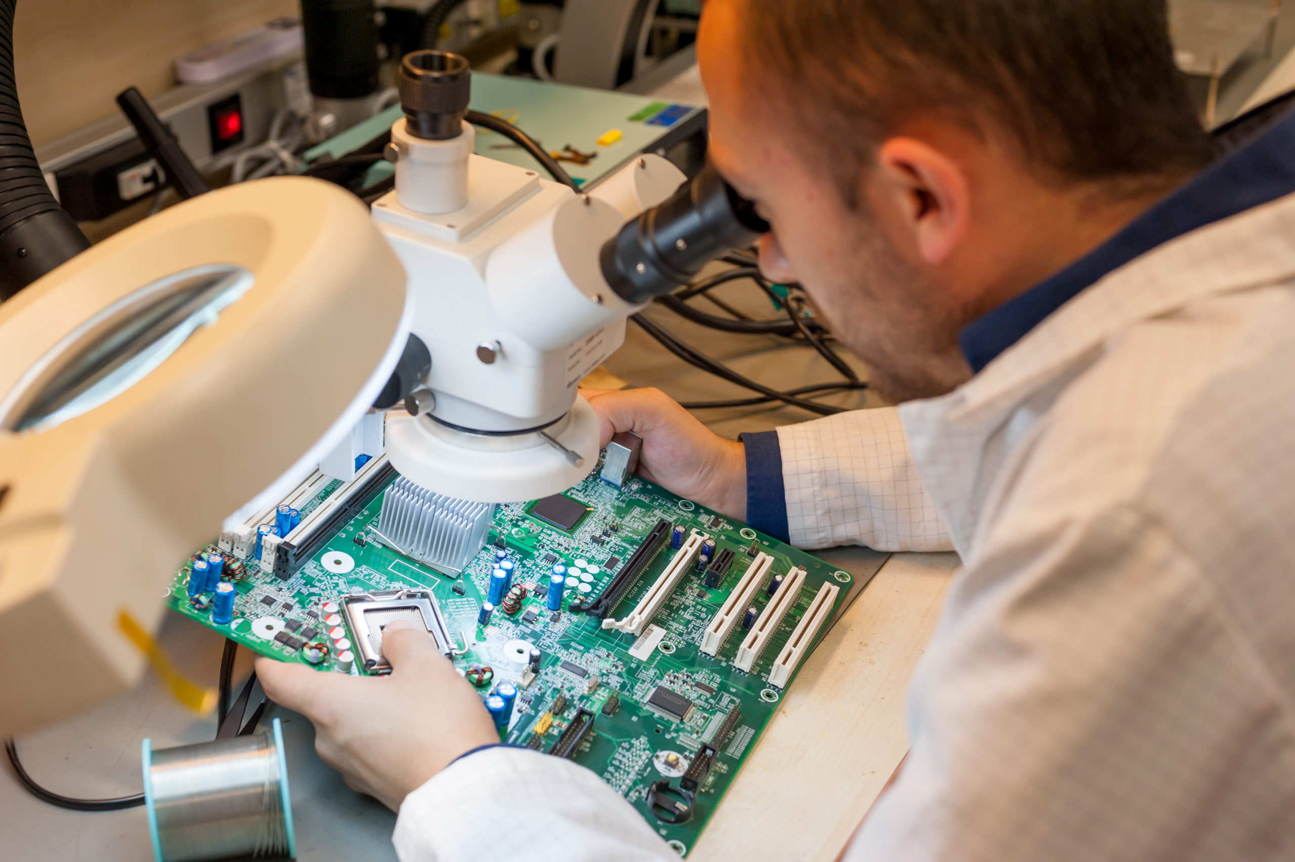 Printed circuit board quality control specialist looking at a PCB